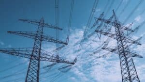 High voltage transmission towers stretch across a clear blue sky, symbolizing energy and industry.